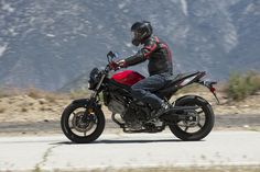 a man riding on the back of a red motorcycle