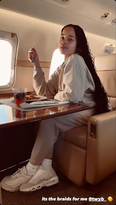 a woman sitting at a table with food and drinks in front of her on an airplane