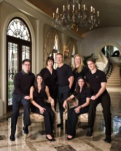 a group of people are posing for a photo in front of a chandelier