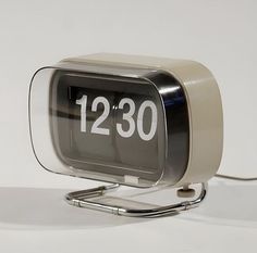 an alarm clock sitting on top of a metal stand with the time 12 30 in front of it