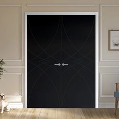 a dog sitting on the floor in front of a black door with an abstract design