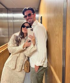 a man and woman taking a selfie in an elevator with their cell phone up against the wall