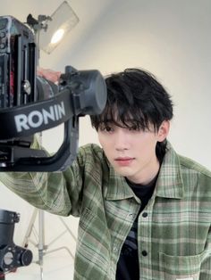 a young man holding up a camera in front of his face and looking at the camera