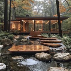 a house in the woods surrounded by rocks and water