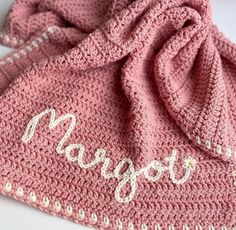 a pink crocheted blanket with the word mama written on it and an embroidered name