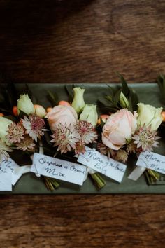 flowers are arranged on a green tray with name tags attached to the stems and leaves