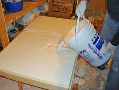 a person pouring paint onto a table with some buckets on it and other items in the background