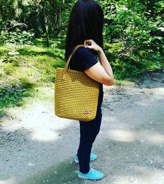 a woman standing on a dirt road holding a yellow basket in front of her face