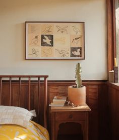 a small cactus sits on a table next to a bed in a room with wood paneling