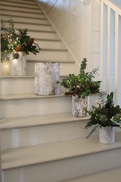 three planters sitting on top of some steps next to a banister with greenery in them