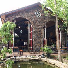 the outside of a building with tables and chairs next to a pond