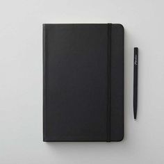 a black notebook and pen on a white surface