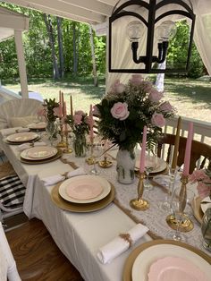 the table is set with pink and white flowers in vases, plates, napkins, and candles