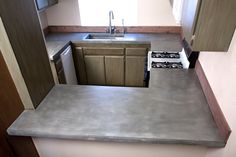 an empty kitchen with stainless steel counter tops and wooden cabinetry, along with a stove top oven