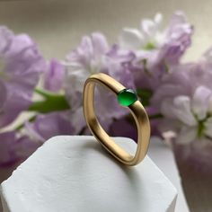 A unique shaped gold ring, its form a symphony of elegance, crowned by a Type A jadeite cabochon. This gem, bathed in a luminous emerald glow, dances with the light of the cosmos, revealing its flawless essence under the natural lighting. Crafted from 18K yellow gold in matt finished, the ring boasts a contemporary allure, its square silhouette softened by gentle curves for a regal yet comfortable fit. A harmonious blend of modernity and tradition, this ring stands as a testament to the opulence Elegant Round Band Jade Jewelry, Yellow Gold Chalcedony Jewelry For Anniversary, Formal Jade Ring Jewelry, Modern Gold Emerald Ring, Yellow Gold Emerald Ring With Chrysoprase For Anniversary, Modern Green Jewelry For Anniversary, Fine Jewelry Chrysoprase For Formal Occasions, Chalcedony Yellow Gold Jewelry For Anniversary, Elegant Jade Ring With Round Band