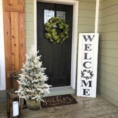 a white christmas tree sitting on the front porch next to a welcome sign and wreath