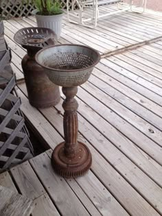 an old metal bowl sitting on top of a wooden deck next to a potted plant