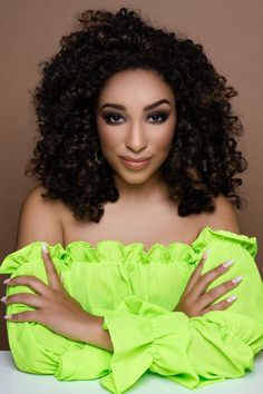 a woman with curly hair and green dress posing for the camera