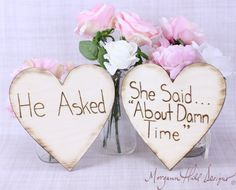 two heart shaped wooden signs with flowers in the middle and one saying she asked about damn time