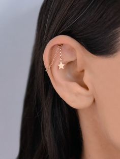 a close up of a person wearing a gold ear cuff with stars on the side