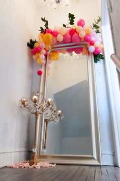 a mirror with some balloons on it and a chandelier in front of it