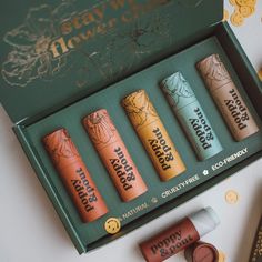 four lip bales are in a green box with gold coins around them and on the table