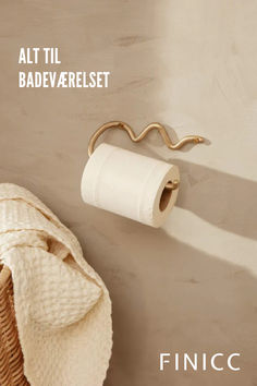 a white towel hanging on the wall next to a toilet paper roll and a basket