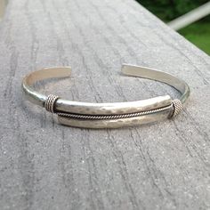 This cuff is made of solid sterling half round wire, joined for 1 3/4 inches at the center, hammered, and then wrapped with twisted sterling wire to give it an accent. The whole bracelet is oxidized, then polished to a medium shine to bring out the detail. It has a low profile and width (3 x 5 mm/10 mm at center - 1/8 inch thickness x 3/16 wide/3/8 at the center), but is work hardened and sturdy. Bracelet shown is for an 8 inch wrist. Will make to size - select wrist measurement from dropdown me Mens Silver Cuff Bracelet, Mens Sterling Silver Bracelets, Rustic Cuff Bracelets, Hammered Bracelet, Silver Jewelry Diy, Rustic Cuff, Mens Cuff, Big Little Lies, Minimalist Bracelet