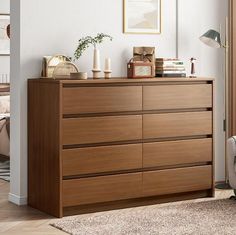 a bedroom with a dresser, chair and pictures on the wall