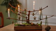 a wooden table topped with a small christmas tree and lit candles in front of it