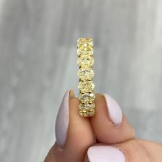 a woman's hand holding a yellow ring with three rows of diamonds on it