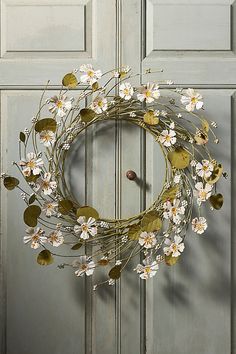 a wreath with white flowers hanging on a door