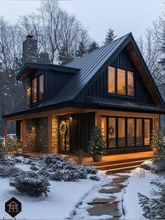 a house that is covered in snow and has lights on the front porch, and steps leading up to it