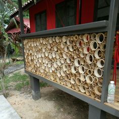 a bench made out of bamboo sticks on the side of a building with red doors