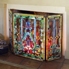 a colorful stained glass fireplace screen sitting on top of a wooden floor next to a fire place