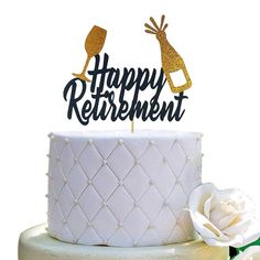 a white cake topped with a gold happy retirement topper and a single white rose