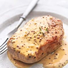 a piece of meat covered in gravy on top of a plate with a fork