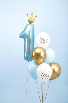 blue and gold balloons with one balloon in the shape of a number on it, sitting next to a cake