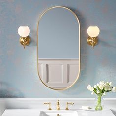 a bathroom sink with a mirror above it and flowers in the vase on the counter