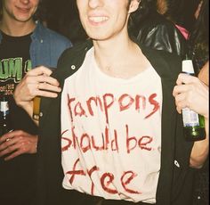 a young man holding a beer and wearing a t - shirt with words written on it