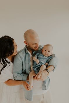 a man and woman holding a baby in their arms