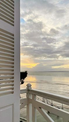 an open door leading to a balcony with the ocean and sky in the background at sunset