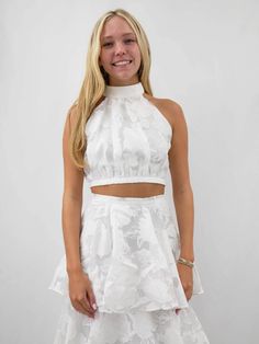 Elevate your formal wardrobe with this exquisite white layered two piece set, perfect for bridal occasions and elegant events. Featuring a sophisticated high halter neck with a zipper closure at the back, this set is crafted from a delicate, floral-patterned fabric that exudes romance and grace. The fitted bodice reveals a subtle midriff before flowing into a voluminous, tiered skirt with cascading ruffled layers that create a dreamy, ethereal silhouette. Each tier is intricately detailed, showc Fitted Hand-embellished White Sets, White Printed Sleeveless Set, White Embellished Sleeveless Set, White Embellished Semi-stitched Sets, White Sleeveless Ruffled Sets, Black Date Night Outfit, White Two Piece Set, Black Dating, White Two Piece