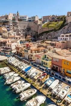 many boats are parked in the water next to some buildings and cliffs with houses on them