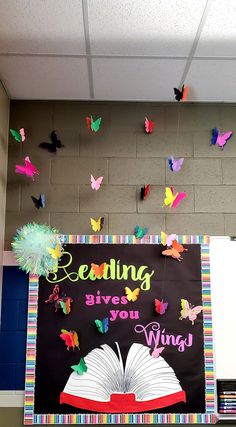 a bulletin board with butterflies on it and a book in the middle that says reading gives you wings