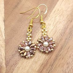 These blushed pink and gold earrings are very light weight, half an inch wide with a little over an inch drop. The flower shaped earrings are made of blushed pink and gold glass twin beads, gold glass seed beads, with a pearl center. The earring wires are hook style. Hooks are gold, nickel-free and hypo-allergenic. Earring backs are made of clear silicone. Perfect for any fall gathering, holiday party, or paired with some cute jeans or leggings!  Please feel free to message me if you have any qu Handmade Gold Pearl Earrings In Flower Shape, Handmade Dainty Gold Crystal Earrings, Gold Beaded Flower Earrings With Ear Wire, Gold Flower Beaded Earrings As Gift, Gold Flower-shaped Beaded Earrings With Ear Wire, Handmade Gold Flower Earrings With Round Beads, Handmade Rose Gold Flower Dangle Earrings, Handmade Rose Gold Flower Drop Earrings, Gold Beaded Dangle Flower Earrings