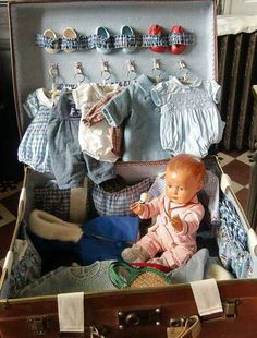 a doll sitting in an open suitcase with clothes hanging on the wall and other items