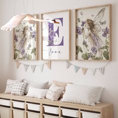 three framed pictures hang on the wall above a bench filled with pillows and storage bins