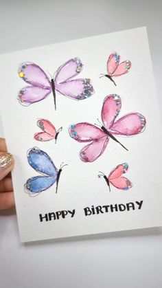 a hand holding up a card with watercolor butterflies and the words happy birthday on it