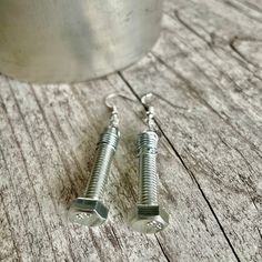 two screws are sitting next to each other on a wooden table with a cup in the background